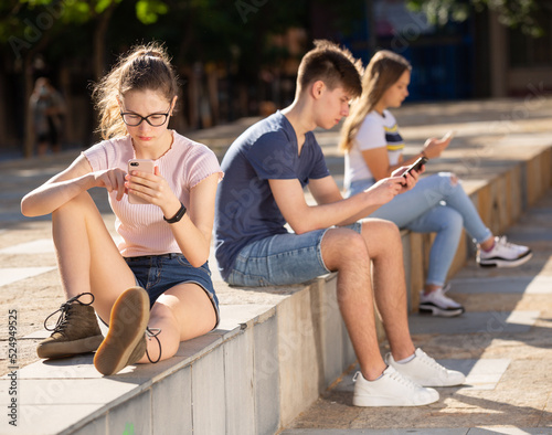 Three teenagers chatting on their smartphone on walking