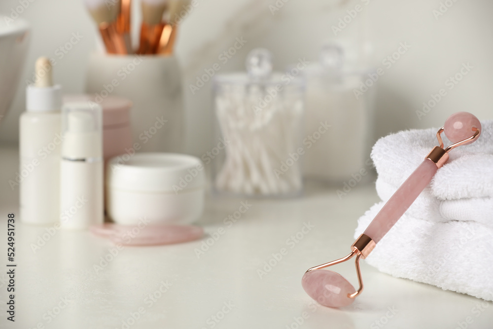 Natural face roller, gua sha tool and cosmetic products on counter in bathroom Natural face roller, gua sha tool and cosmetic products on counter in bathroom