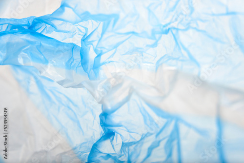 White and blue plastic background, wrinkled single use bag. Concepts: sustainability, recycling, pollution.