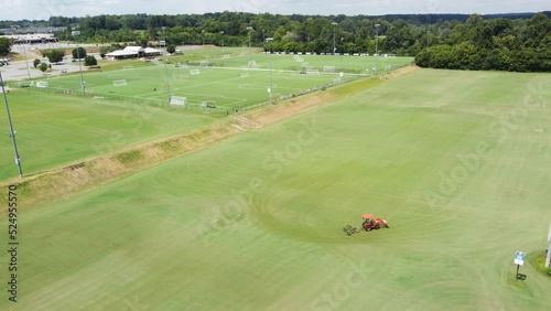 Orange Tractor mowing Sports complex fields photo