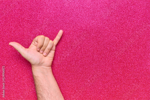 hand shaka relaxed gesture with pink glitter background