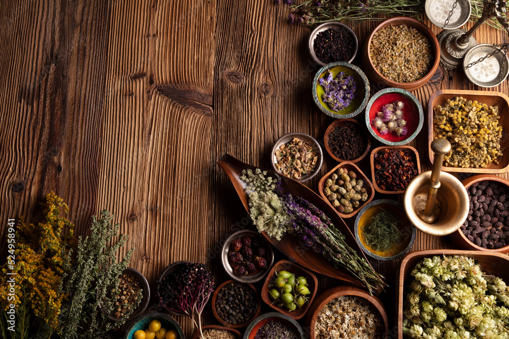 Natural medicine background. Assorted dry herbs in bowls, mortar and plants on rustic wooden table.