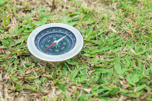 The compass is placed on the green grass showing north south east west