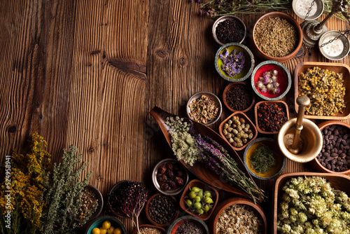 Natural medicine background. Assorted dry herbs in bowls  mortar and plants on rustic wooden table.