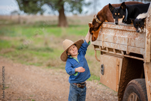 Boy pats his kelpie dog on the back of the farm ute