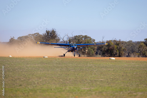 small plane taxiing on unsealed dusty runway in rural area photo