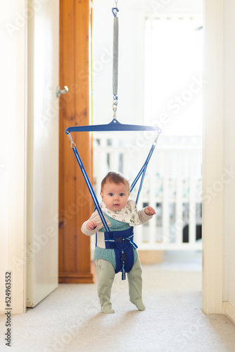 Baby playing in jolly jumper bouncing toy in doorway
