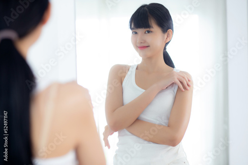 Beautiful young asian woman looking in mirror and apply moisturizer with cosmetic cream or lotion with shoulder in bathroom at home, skincare for hygiene, treatment and bodycare, skin care concepts. Free Download Beautiful young asian woman looking in mirror and apply moisturizer with cosmetic cream or lotion with shoulder in bathroom at home, skincare for hygiene, treatment and bodycare, skin care concepts. - GFXLoad
