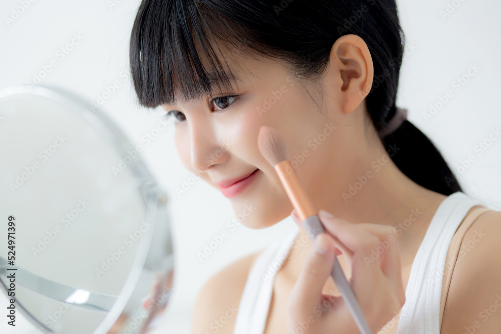 Beautiful young asian woman applying brush on cheek makeup of cosmetic looking mirror on bed, beauty of girl with skin facial and wrinkle in the bedroom, cosmetology for female, skincare concept. Beautiful young asian woman applying brush on cheek makeup of cosmetic looking mirror on bed, beauty of girl with skin facial and wrinkle in the bedroom, cosmetology for female, skincare concept.