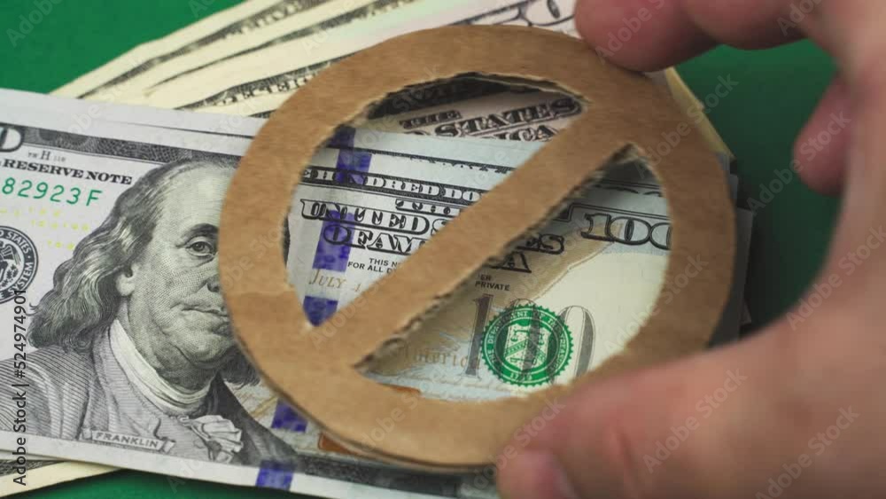 Economy concept. On US dollars, a man's hand puts a prohibition sign.