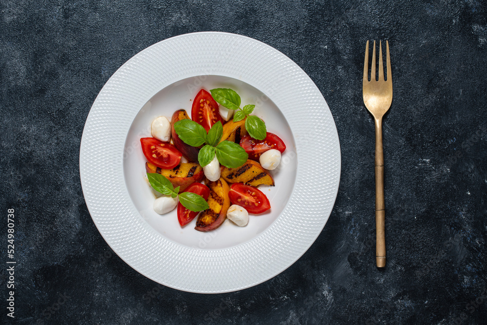 Grilled peach salad with mozzarella, tomato, green basil and sauce, close up, top view Grilled peach salad with mozzarella, tomato, green basil and sauce, close up, top view