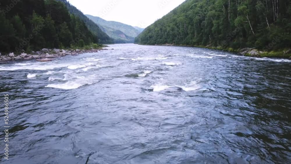 Flow of a mountain river among mountain hills covered with green forest. Flying with a top view of a wildlife landscape Flow of a mountain river among mountain hills covered with green forest. Flying with a top view of a wildlife landscape