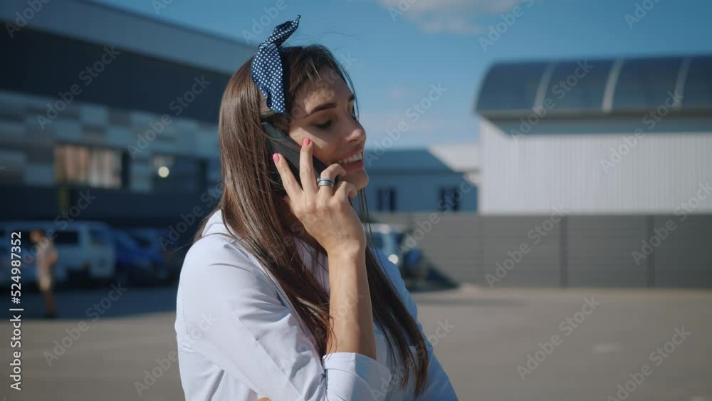Smiling Young Business Woman in White Shirt is Talking on Phone Outside near Modern Office Building. Attractive Female with Long Hair Talking on Mobile Phone while Standing Outdoors on a City Street. Smiling Young Business Woman in White Shirt is Talking on Phone Outside near Modern Office Building. Attractive Female with Long Hair Talking on Mobile Phone while Standing Outdoors on a City Street.