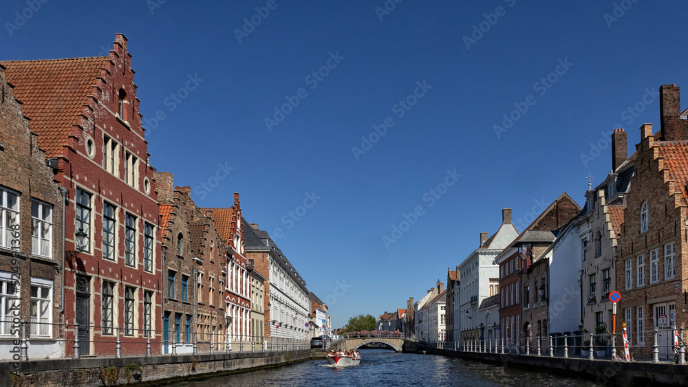 BRUGES, BELGIUM - AUGUST 11, 2022:  Panorama view of canal with sightseeing tour boat