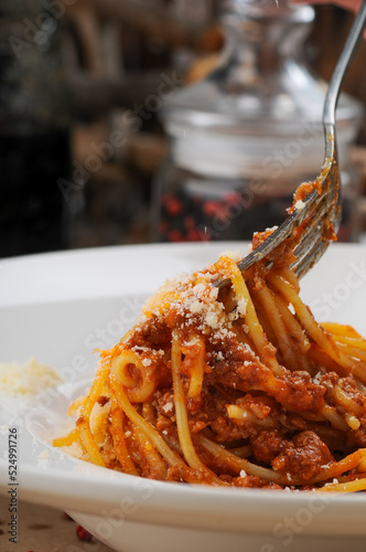 italian pasta with sauce in a white plate with a fork in hands macro photo
