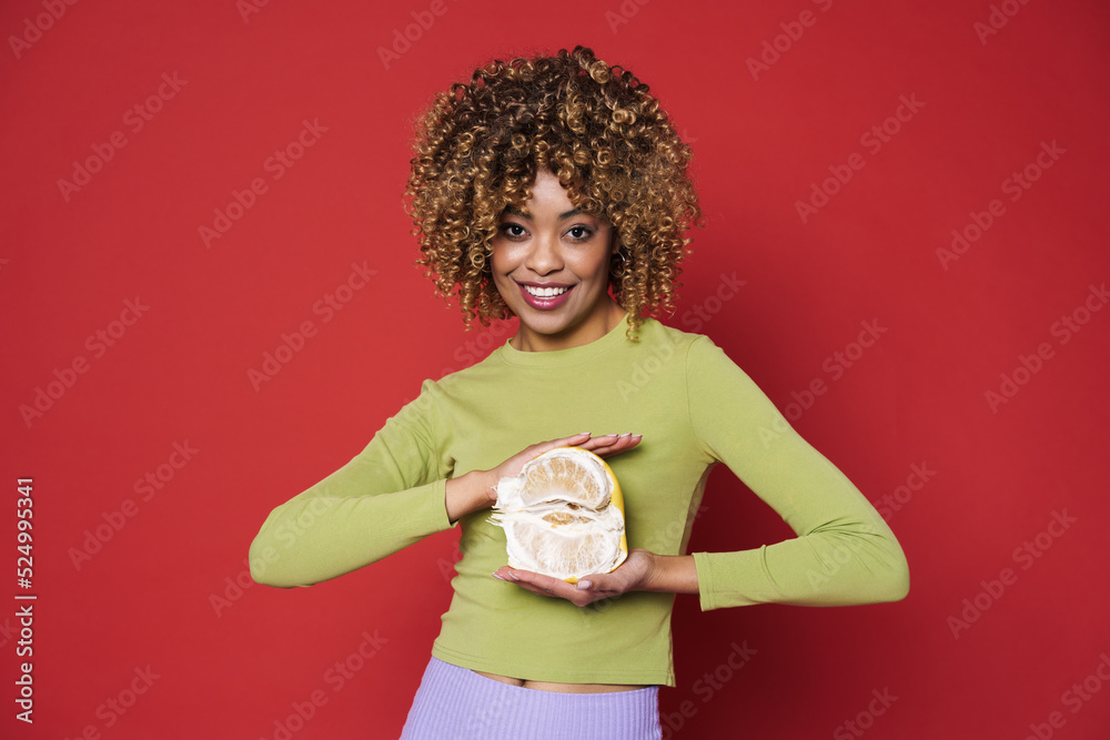 Young black woman laughing while posing with grapefruit