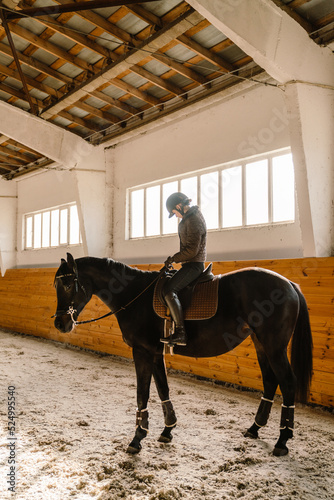 Jockey woman wearing helmet riding her horse during equestrian practice © Drobot Dean