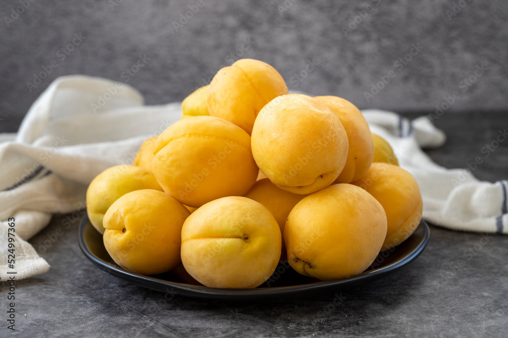 Ripe apricots on a dark background. Fresh and juicy apricots on the plate. Organic food. close up