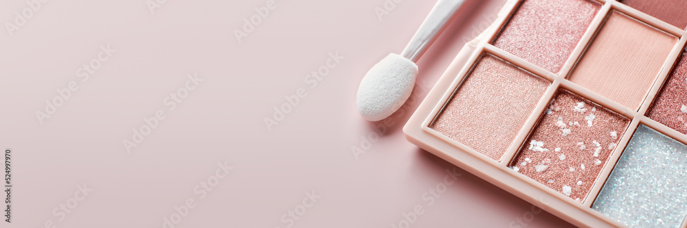 Fototapeta premium Eyeshadow colorful shades palette in beige tones and brush close-up. Beauty abstract banner