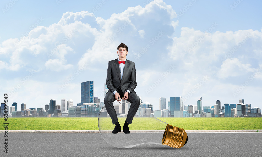 businessman with glasses sits on a light bulb businessman with glasses sits on a light bulb