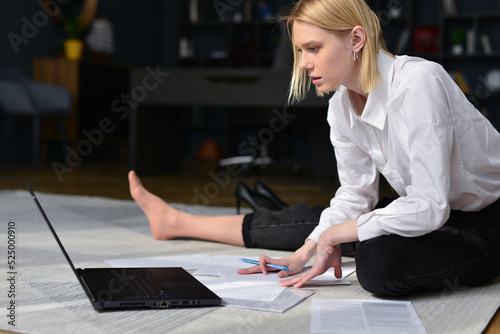 Woman sits on floor with her laptop and works