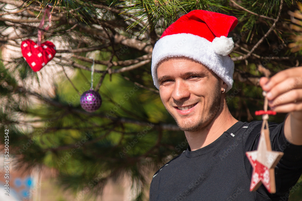 young man with christmas ornament decorating christmas tree young man with christmas ornament decorating christmas tree