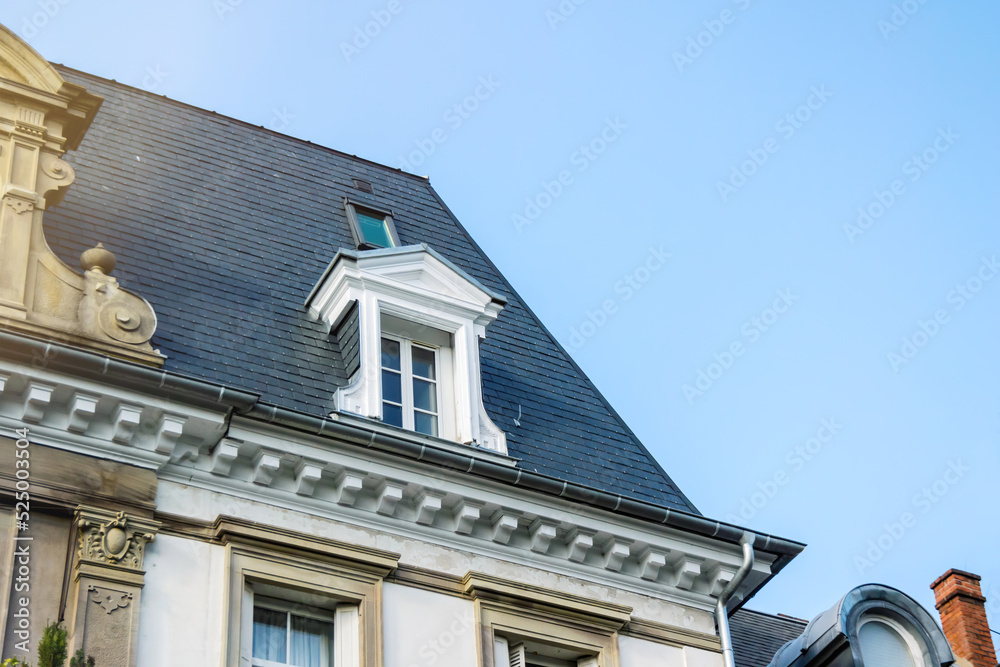 French rooftop with mansard window with blue sky in the background - luxury real estate in French city urban area