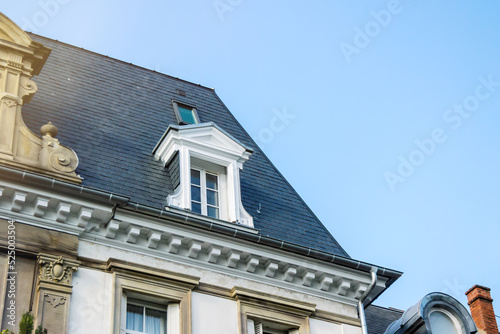 French rooftop with mansard window with blue sky in the background - luxury real estate in French city urban area