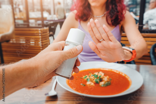 The woman refuses to add salt to her dish in the restaurant with a gesture No. An overabundance of consumption of this seasoning can lead to cardiovascular diseases and gout