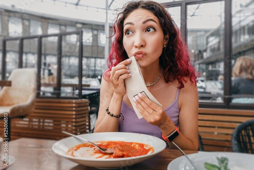 Fotografie The girl observes tact and good manners and wipes her mouth after a hearty meal in a cafe