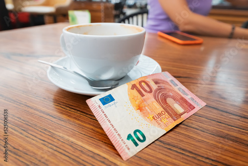 The client left a generous tip after breakfast in the cafe. Ten euro banknote on a table