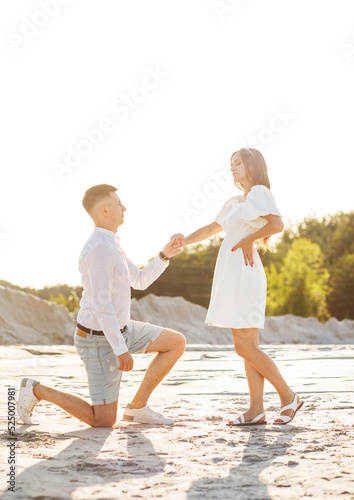 The moment of marriage proposal at sunset. A man on one knee in front of a woman