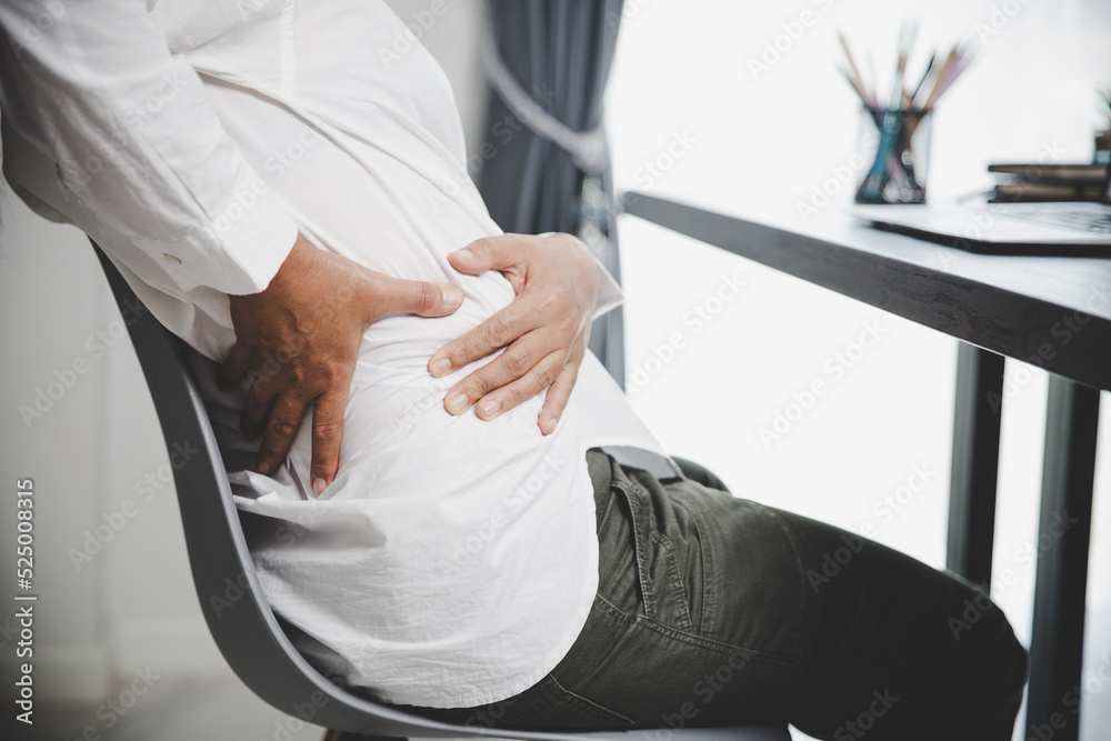 Young asian woman is sitting at work and has tension pain in her neck. Concept office syndrome backache pain from occupational disease, Female having muscle pain from using laptop computer, back pain.