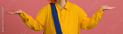 a clown in a yellow-blue suit spread his arms to the sides on a colored background, close-up