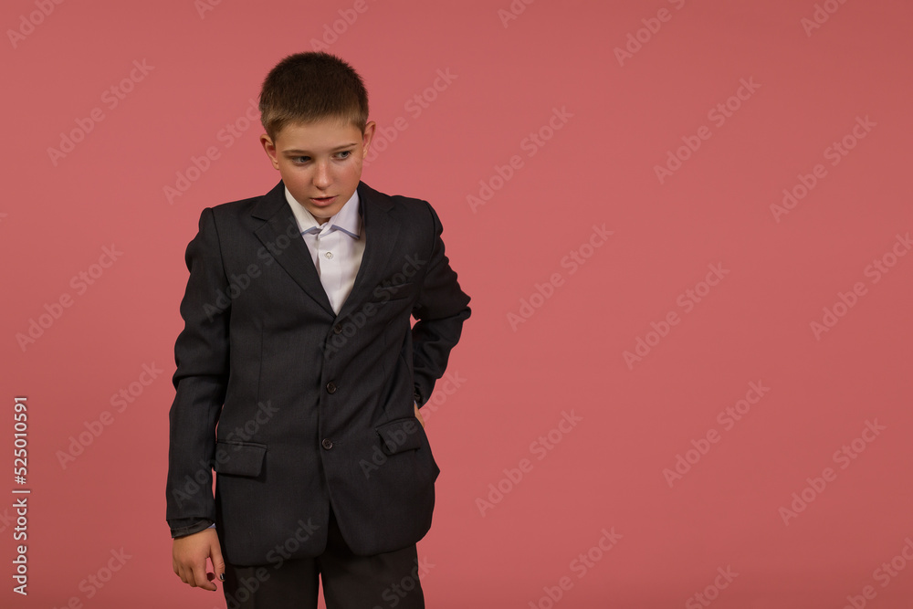 schoolboy in black suit on pink background with copy space