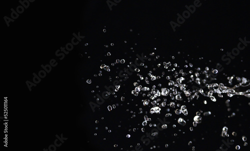 horizontal image. Water splashes in the air. Water waves and airdrops, natural air water movement and black background.