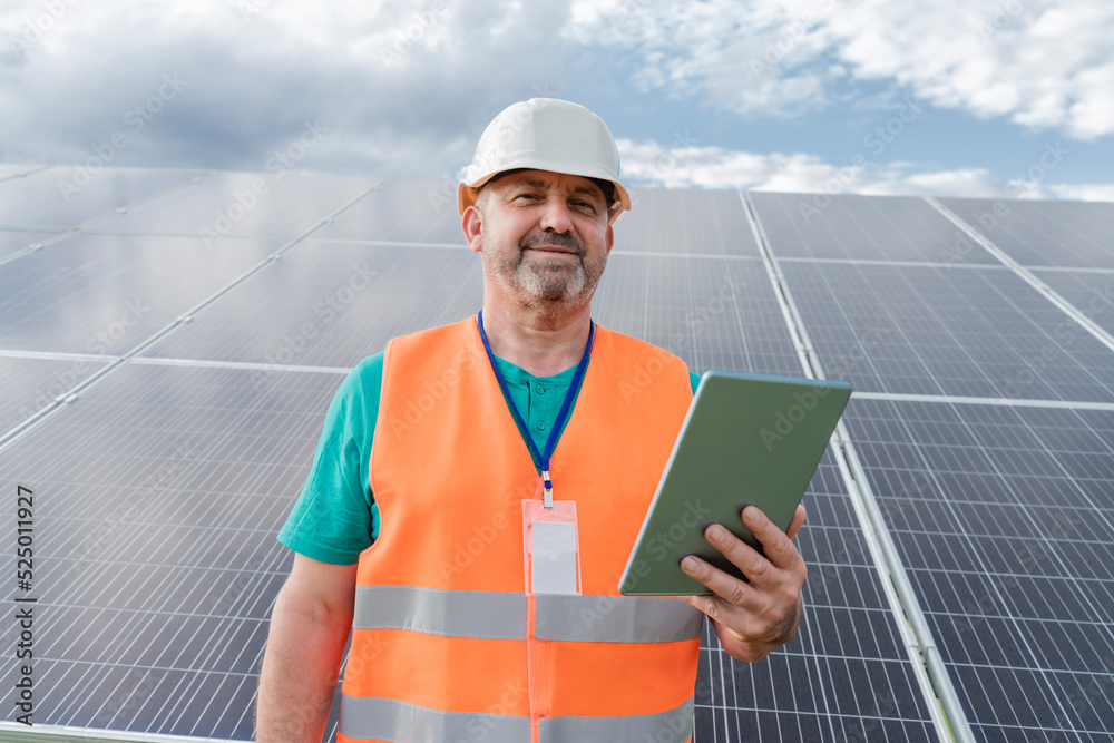 Engineer with tablet PC in front of solar panels Engineer with tablet PC in front of solar panels