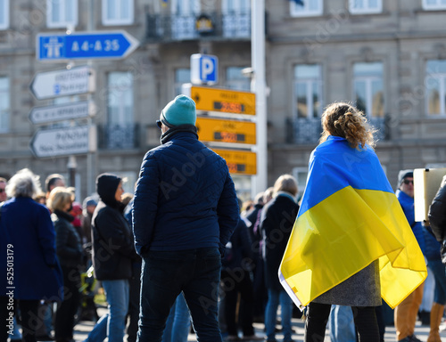 Rear view of woman wearing Ukrainian flag walking on street at protest in front of Russian Consulate solidarity Ukrainians against the war after Russian invasion