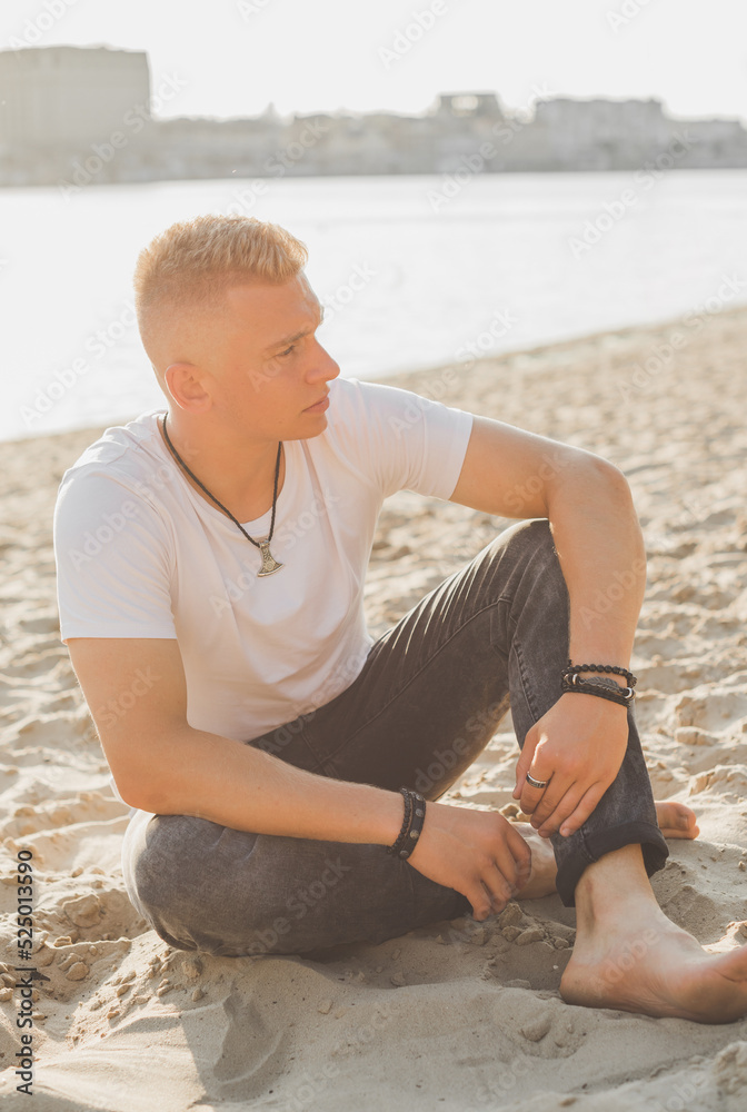 Young guy at beach in tranquility mood, rest in vacation. Summer portrait of handsome men at beach, concept of vacation, rest time Young guy at beach in tranquility mood, rest in vacation. Summer portrait of handsome men at beach, concept of vacation, rest time