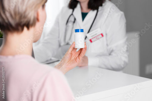 A woman holds a white jar of medicine  a doctor is in the background