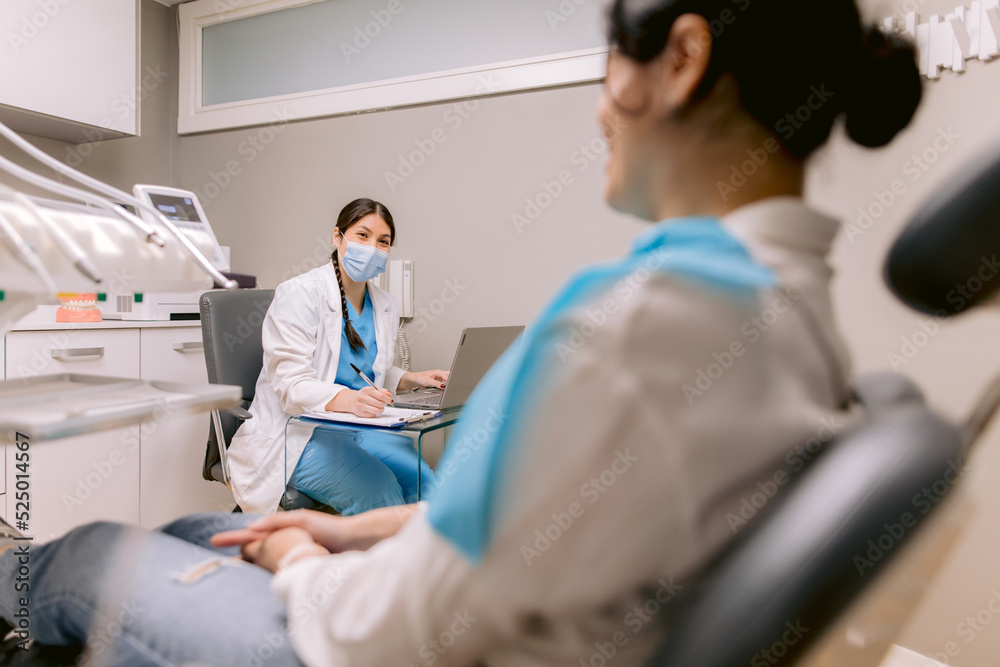 Dentist with laptop talking to unrecognizable patient in hospital Dentist with laptop talking to unrecognizable patient in hospital