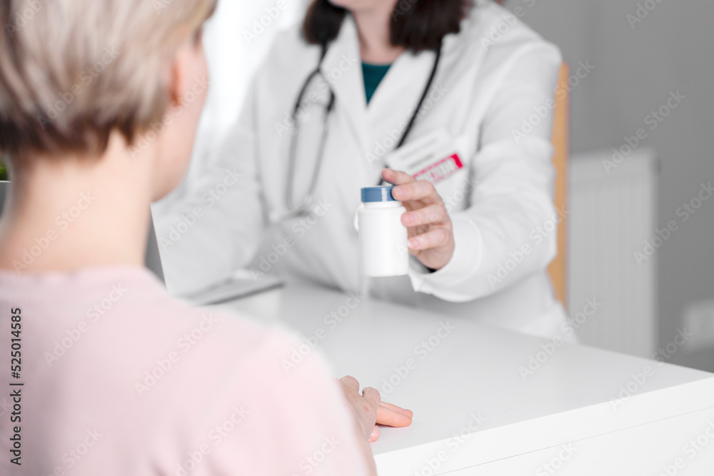 The doctor gives his patient a white jar of medicine and pills. The doctor gives his patient a white jar of medicine and pills.
