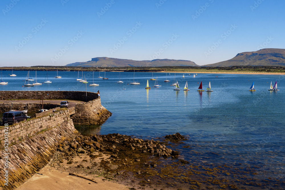 Yachts sailing in the ocean. Warm sunny day. Mountains in the background. Blue water and clean sky. Mullaghmore area, county Sligo, Ireland. Popular holiday area with stunning nature scenery.