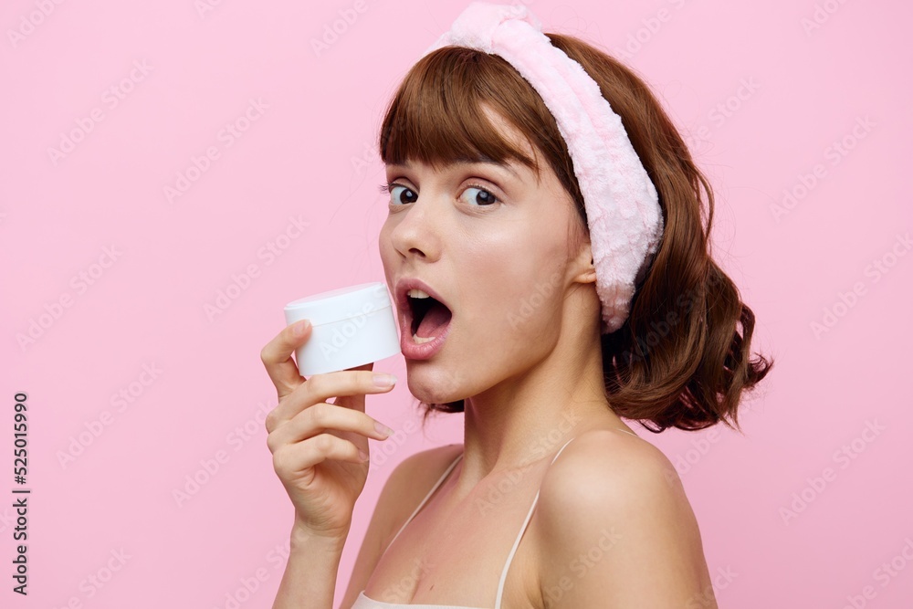 a happy, joyful, young woman stands squinting her eyes from a smile and holds a round, white jar of cream in her hand a happy, joyful, young woman stands squinting her eyes from a smile and holds a round, white jar of cream in her hand