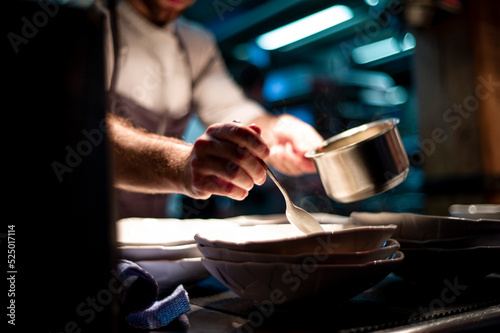Hands of cook adding sauce in plate