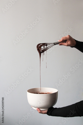 Crop hands draining chocolate from a whisk photo
