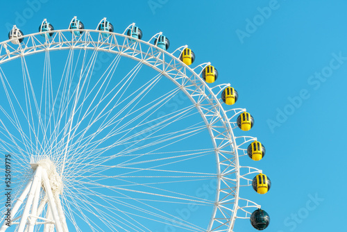 Ferris wheel with colorful cabins on background of the sky close-up.