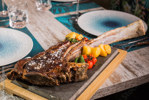 Delicious tomahawk steak with vegetables on cutting board