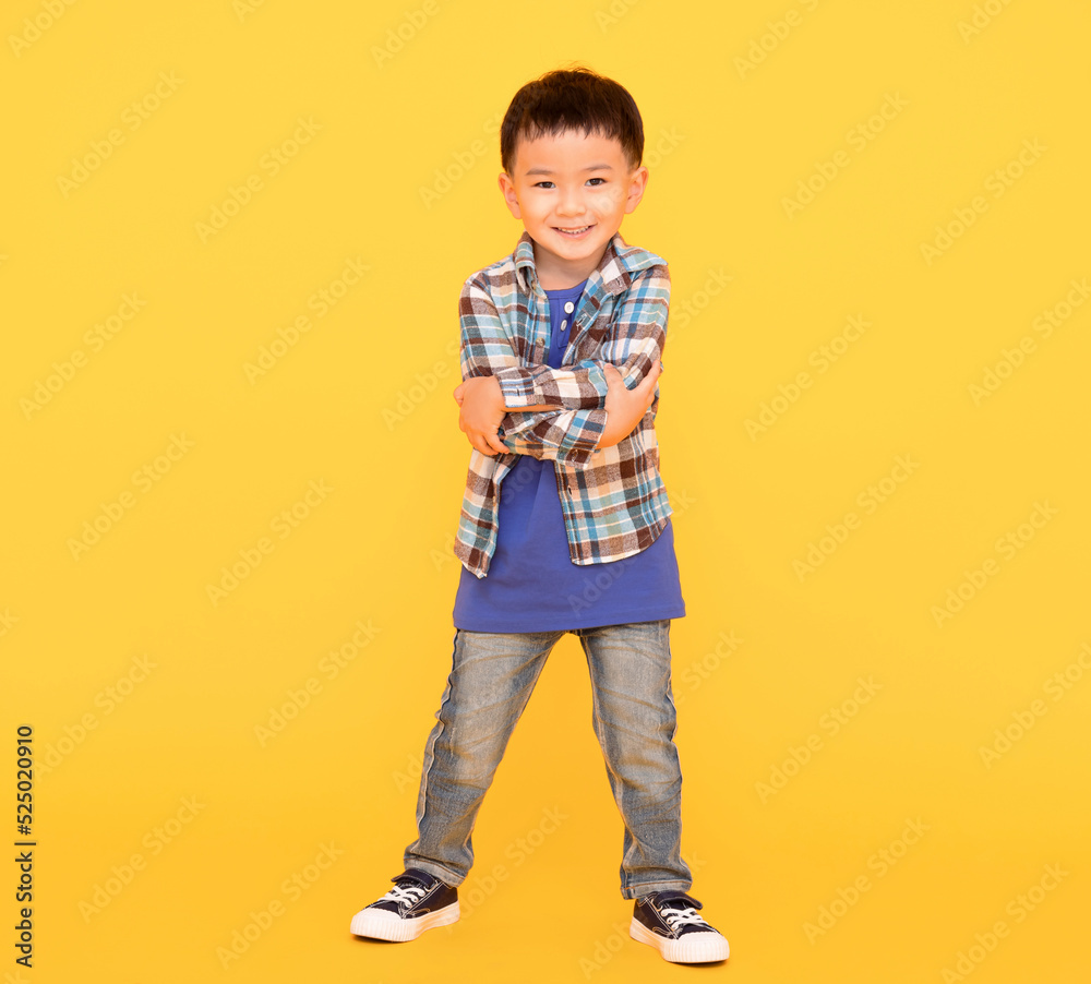 happy asian kid standing  over yellow background