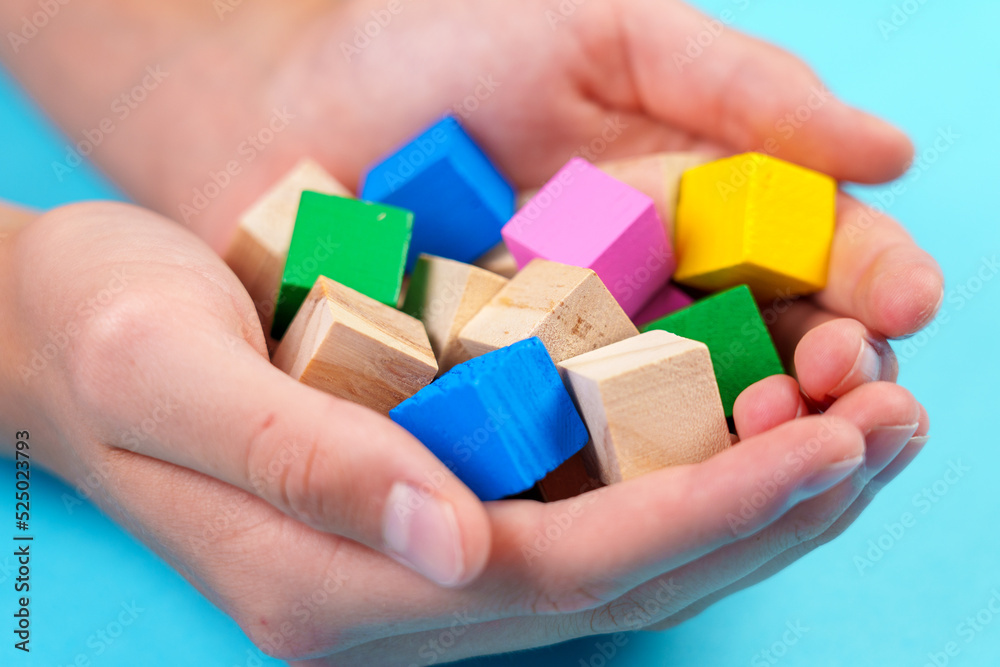 Educational wooden colorful toy blocks close-up on blue background in hands Educational wooden colorful toy blocks close-up on blue background in hands